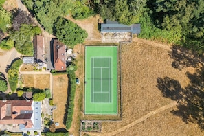 An aerial view of a residential area with a tennis court, houses, and surrounding greenery. - Tea Hut | By My Getaways (Lewes)