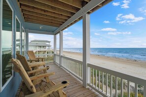 A covered deck with wooden chairs and a view of the beach. - Sunrise Chateau I Beachfront Vacation Home (Bolivar Peninsula)