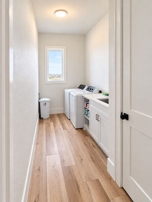 A laundry room with a washing machine, dryer, and a window with a view. - Sunrise Chateau I Beachfront Vacation Home (Bolivar Peninsula)