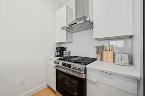Eine moderne Küche mit Gaskochfeld, Backofen und Kaffeemaschine.