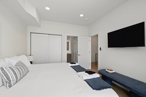 Ein modernes Hotelzimmer mit einem großen Bett, einem flachbildfernseher an der Wand und einer Bank mit einer Schale Snacks.