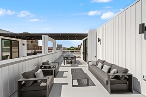 Een terras buiten met zitplaatsen en een eethoek, met uitzicht op een stadsgezicht.