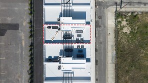 Ein Luftbild eines Gebäudes mit Parkplatz, einem eingezäunten Bereich und einer angrenzenden Straße.