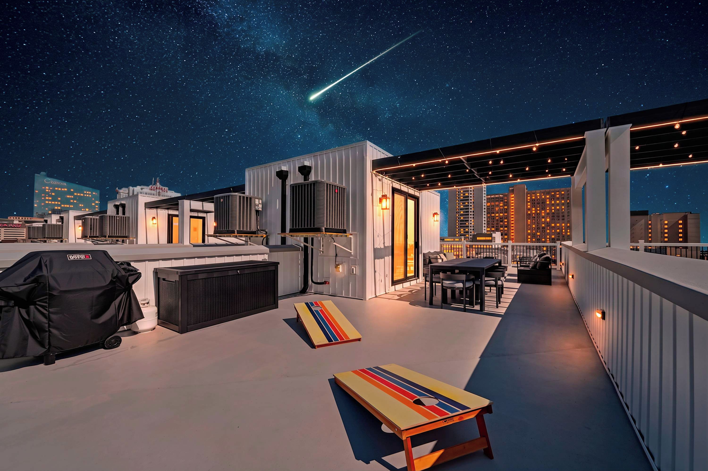Une terrasse sur le toit offrant une vue dégagée sur le ciel nocturne, un espace repas et un jeu de société coloré à rayures.
