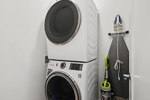 Eine platzsparende Waschküche mit Waschmaschine, Trockner und Bügeleisen.