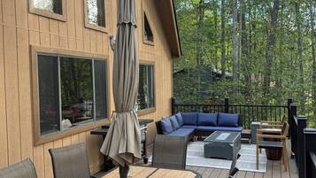A wooden deck with outdoor furniture, including a table and chairs, and a built-in seating area with cushions.