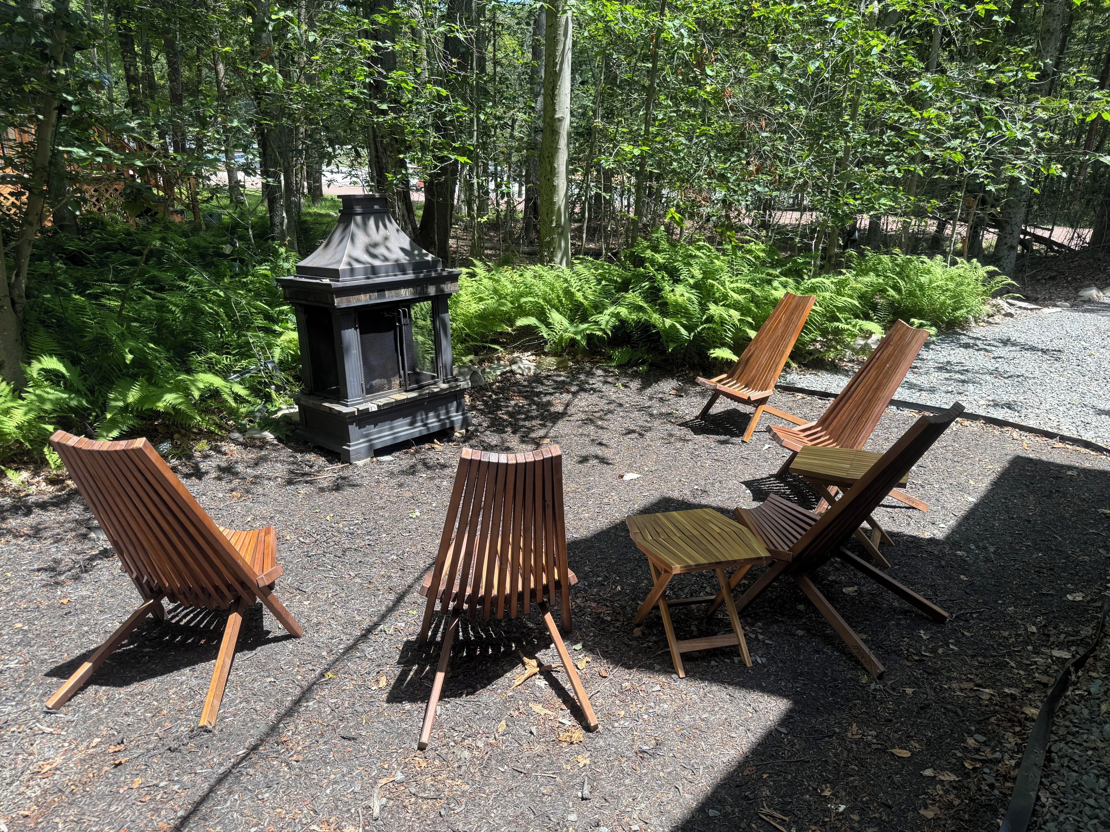 Espace extérieur aménagé avec un foyer et entouré de verdure.