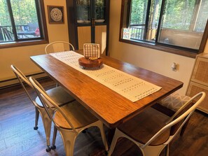 A dining table with a placemat, chairs, and a window with a view of trees.
