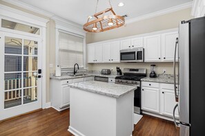 A kitchen with white cabinets, a stainless steel refrigerator, a microwave, a stove, and a blender. - Garden District Luxury Retreat!  Homebase for Sports, Work & Families! (Baton Rouge)