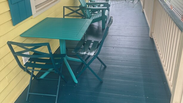 Eine überdachte Veranda mit Tisch, Stühlen und Geländer, mit Blick ins Freie.