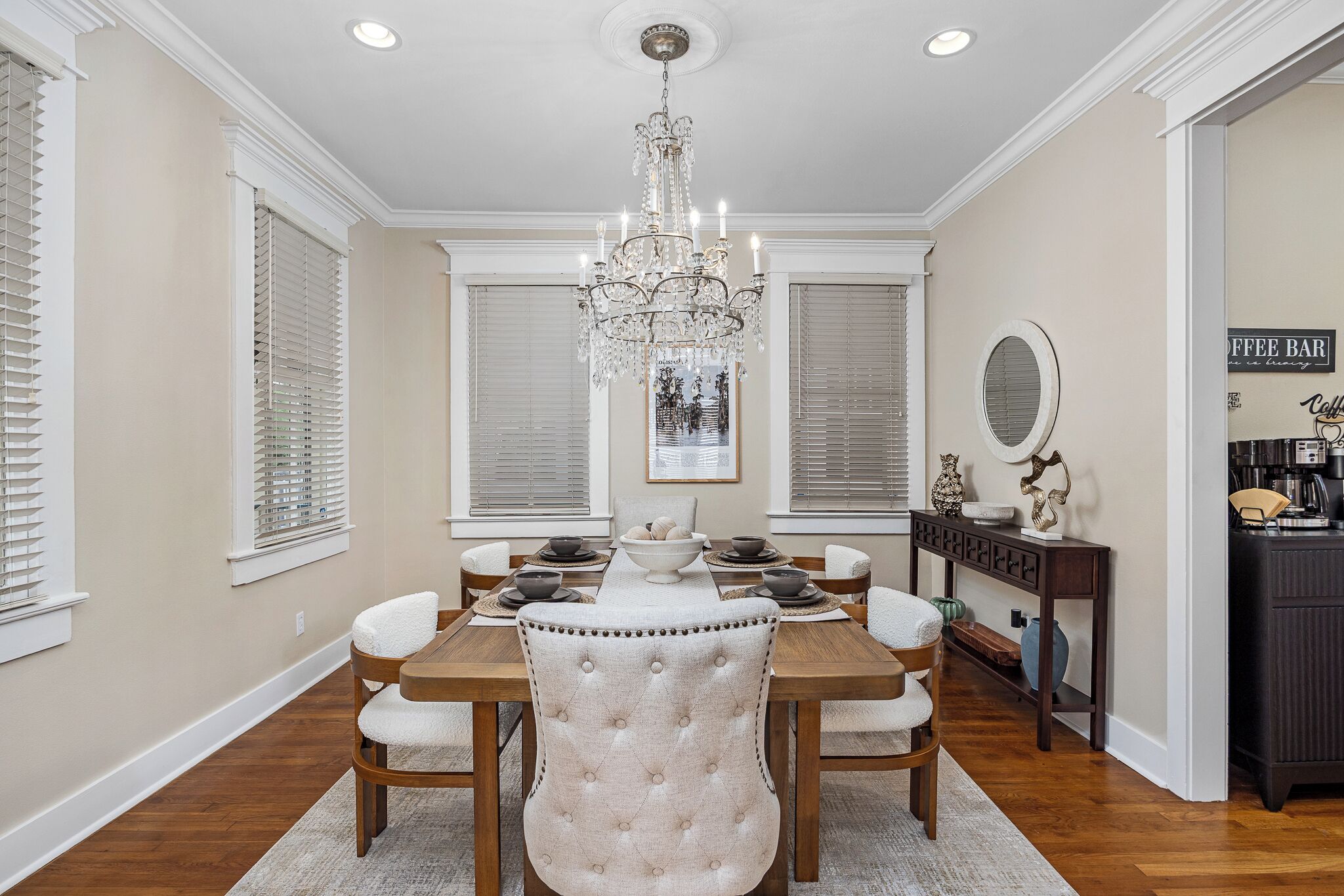 A dining room with a chandelier, a coffee bar, and a framed picture on the wall.