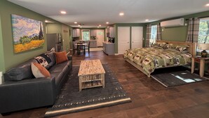 Una habitación con cama, sofá, mesa de comedor y zona de cocina.