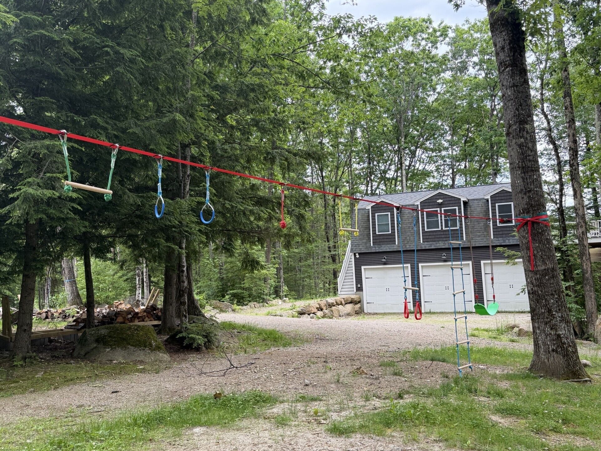 Una casa con garaje, rodeada por un bosque con un columpio.