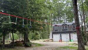Una casa con garaje, rodeada por un bosque con un columpio.