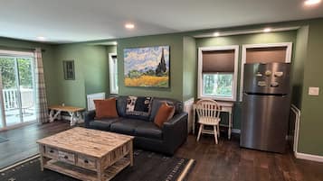 A living room with a sofa, coffee table, and a painting on the wall.