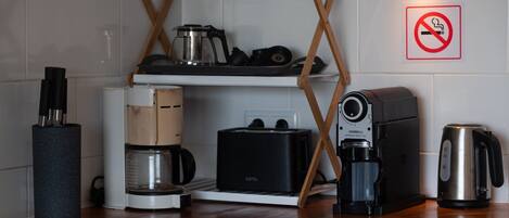 A kitchen with a coffee maker, toaster, kettle, and a no-smoking sign.