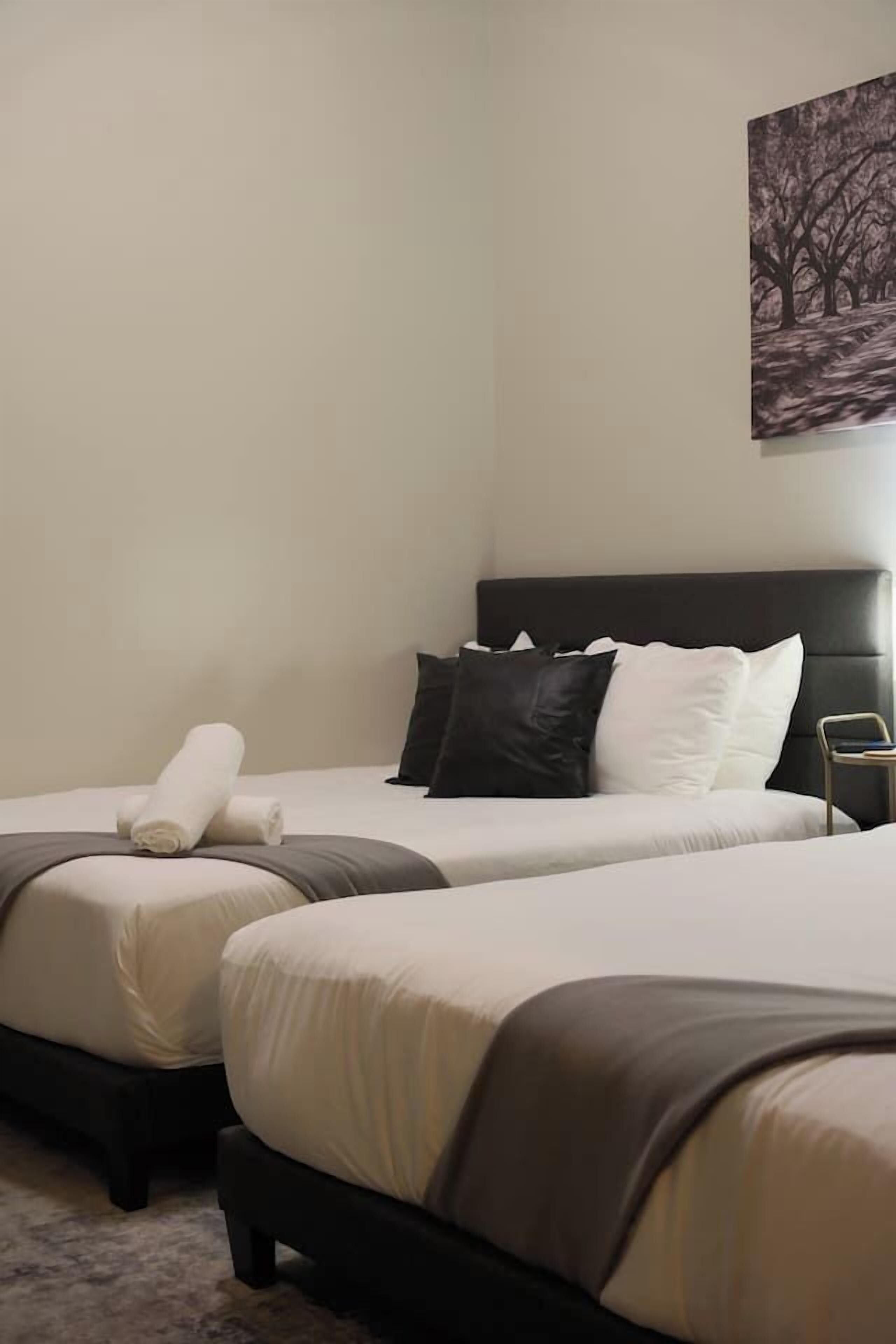A hotel room with two beds, a headboard, and a painting on the wall.