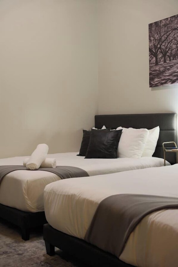 Ein Hotelzimmer mit zwei Betten, einem Kopfteil und einem Bild an der Wand.