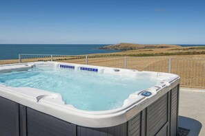 Un jacuzzi con vista despejada al océano y colinas al fondo.