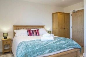 Un dormitorio con cama, lámparas de noche, armario y mesita de noche.