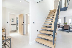 Un interior moderno con una escalera de madera, una zona de cocina y un comedor.