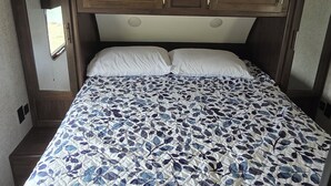 A bedroom with a bed, a headboard, and a window. - Cozy Camper on Current River - Private Boat Ramp with a Dock and Views. (Doniphan)