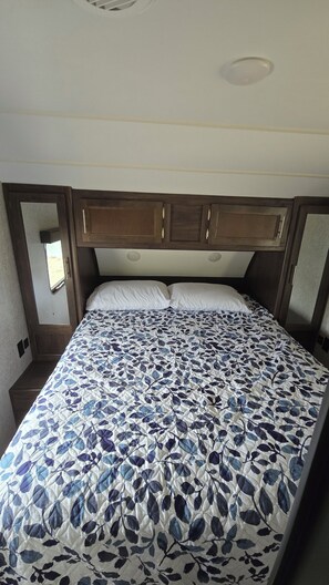 Un dormitorio con cama, cabecera y ventana.