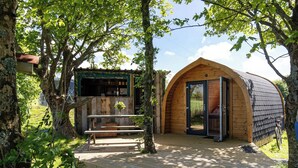 A wooden cabin with an open door, a bench, and a table outside.