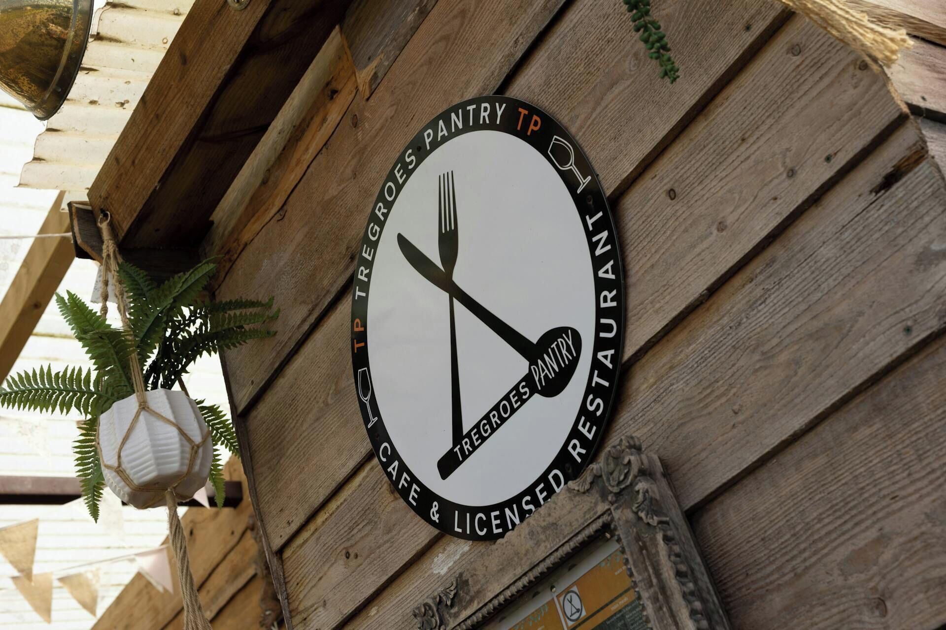 A circular sign with a logo and text indicating a restaurant named 'Tregroes Pantry & Licensed Restaurant.'