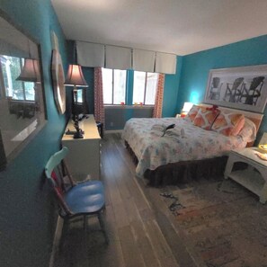 Ein Schlafzimmer mit einem Bett, einem Schreibtisch, einem Stuhl und einem Fenster mit Vorhängen.