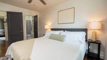 A bedroom with a bed, bedside lamps, a ceiling fan, and a painting on the wall.
