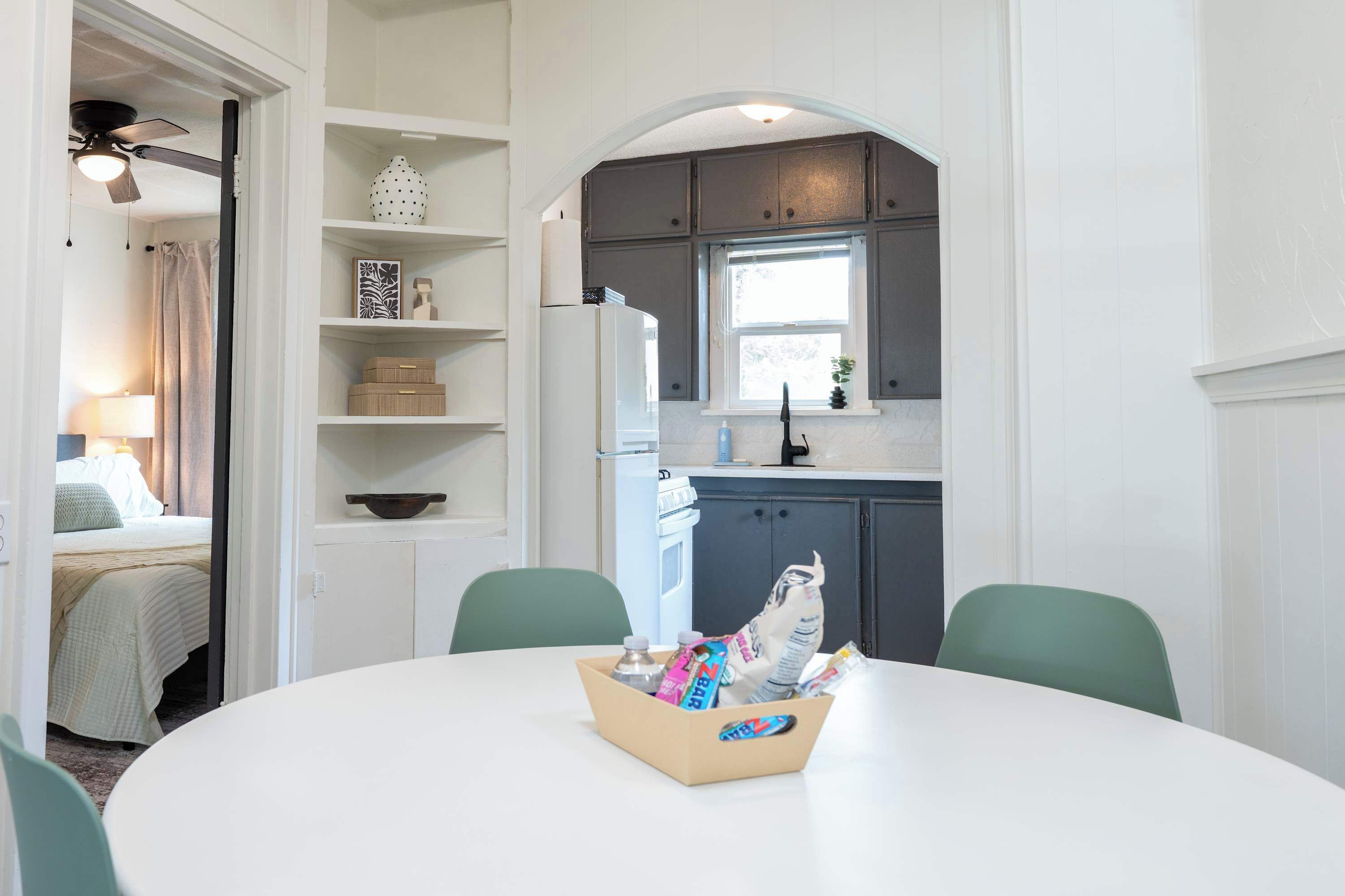 A compact kitchen with a refrigerator, a window, and a dining area with a table and chairs.