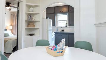 A compact kitchen with a refrigerator, a window, and a dining area with a table and chairs.