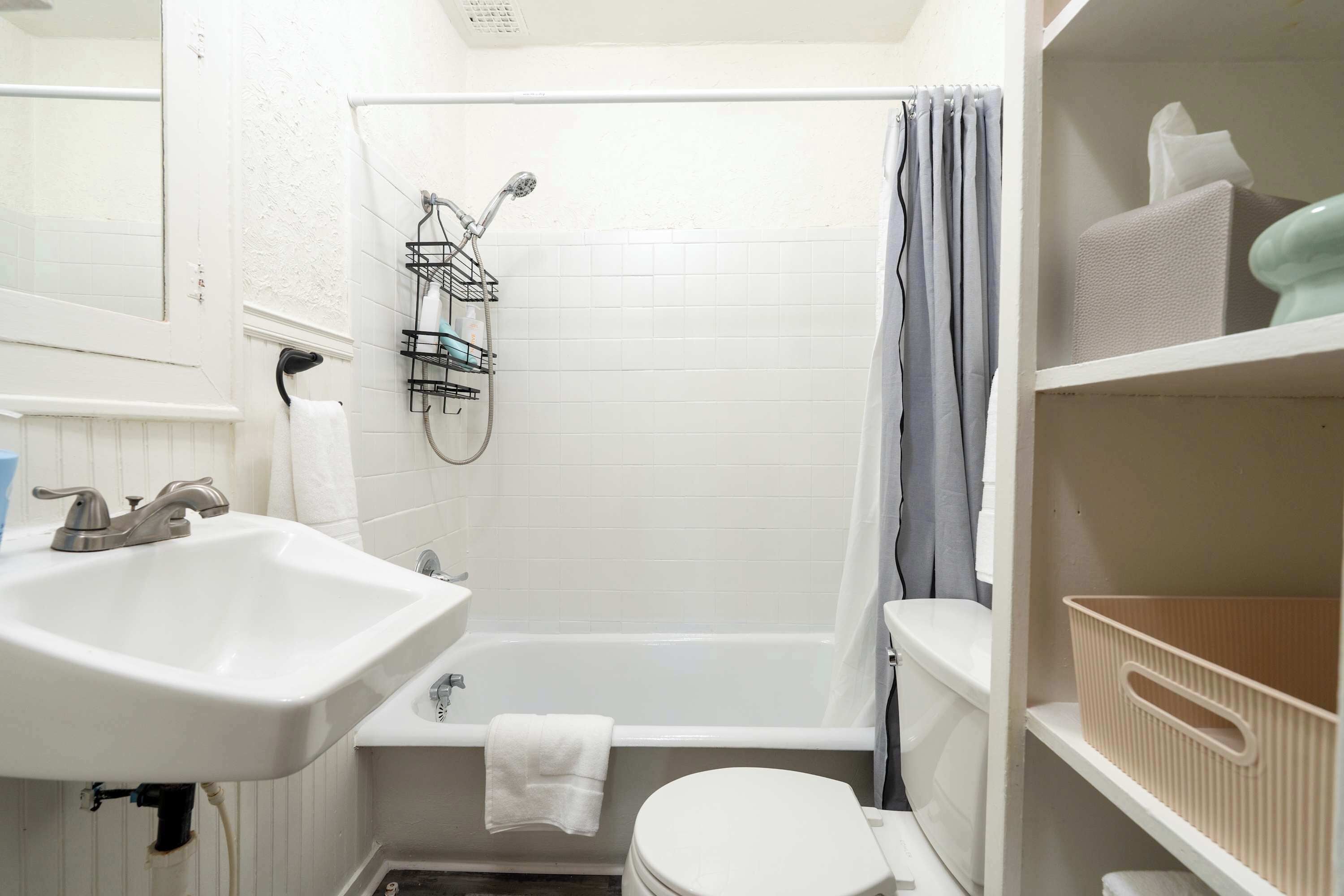 Ein kleines Badezimmer mit einem weißen Waschbecken, einer Toilette, einer Dusche inklusive Handbrause und einem Handtuchhalter.