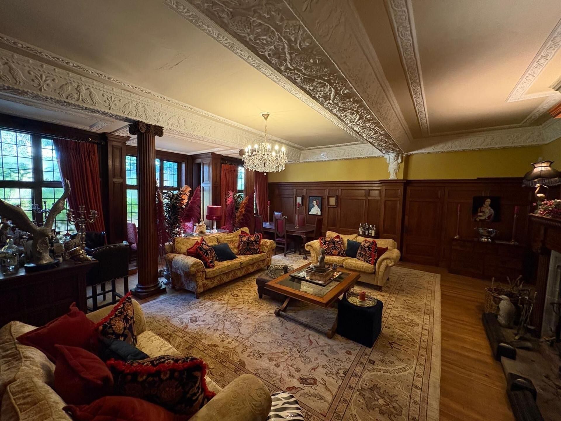 A spacious living room with multiple seating areas, a chandelier, and a fireplace.