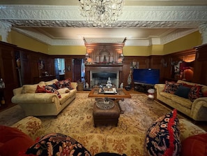 A traditional living room with two sofas, a fireplace, a television, and a chandelier. - Chobham 4-bed House, Sleeps 9 w/ Parking & Garden (Woking)