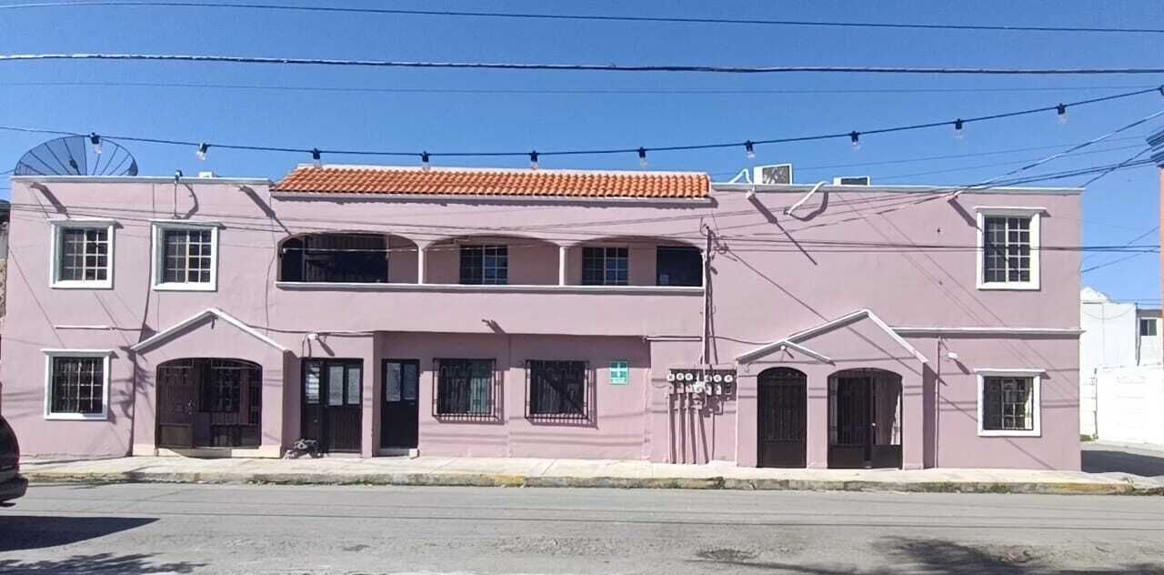 A two-story building with a flat roof and a series of windows on the ground floor.