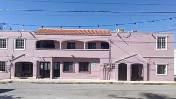 A two-story building with a flat roof and a series of windows on the ground floor.
