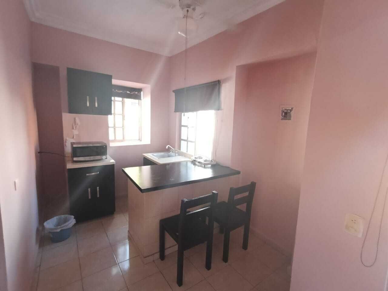 A compact kitchen with a microwave, sink, and a small dining area with two chairs.