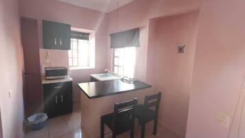 A compact kitchen with a microwave, sink, and a small dining area with two chairs.