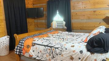 Une chambre dans un chalet en bois, avec un lit, une télévision et une fenêtre avec des rideaux.