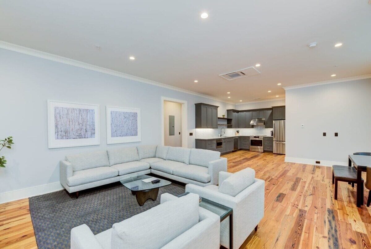 A modern living room with a sectional sofa, a coffee table, and a dining area with a table and chairs.