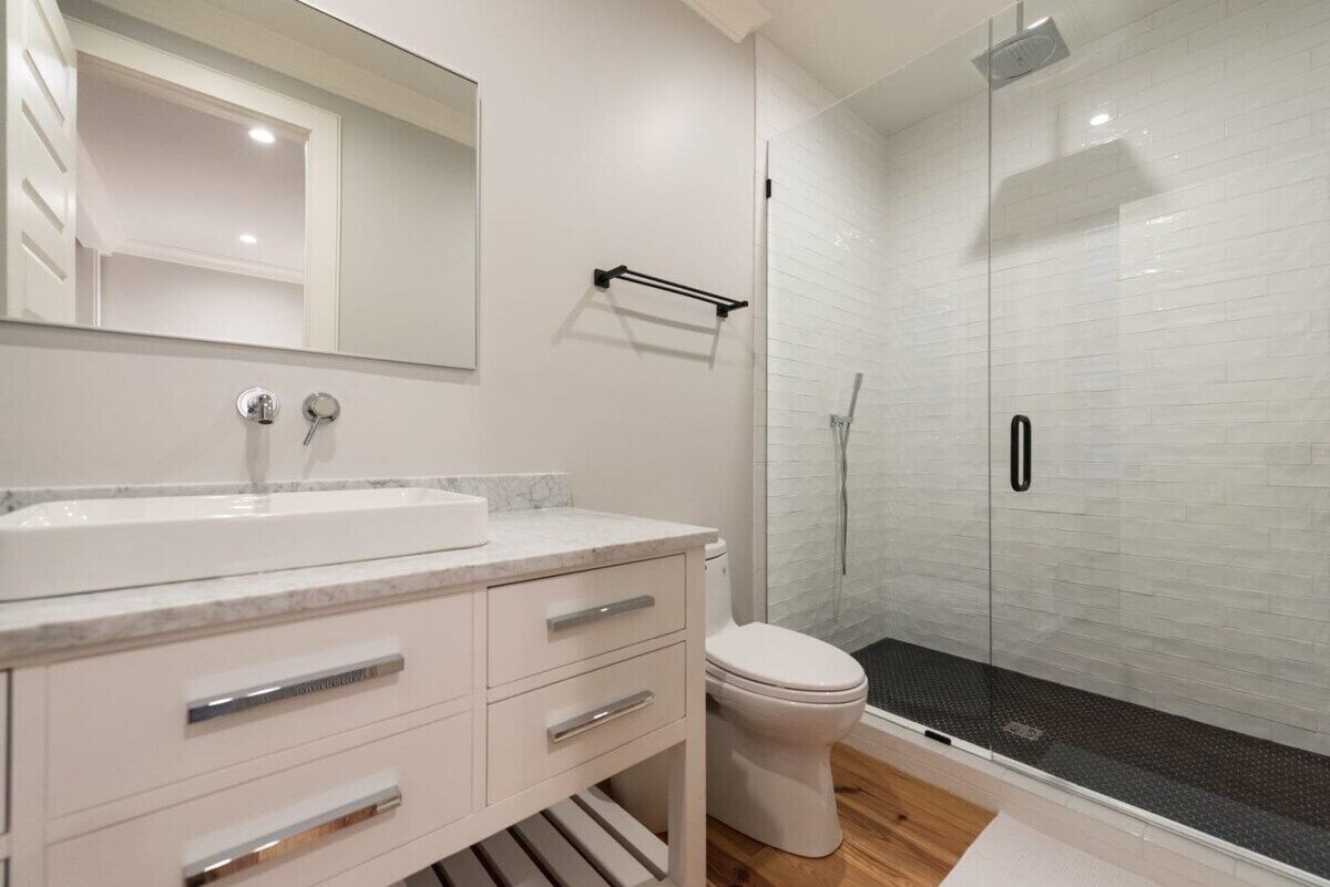 A modern bathroom with a white sink, mirror, and toilet.