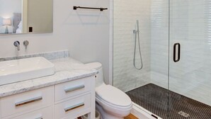 Une salle de bain moderne avec une douche à parois de verre, un lavabo blanc et des toilettes.