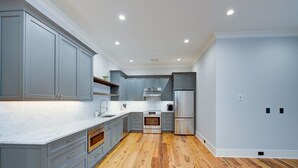 Une cuisine moderne avec des meubles gris, une cuisinière en acier inoxydable et un plancher en bois.