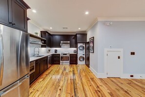 Una cocina moderna con electrodomésticos de acero inoxidable, armarios oscuros y piso de madera.