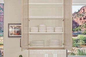 A kitchen cabinet with white storage containers and plates.