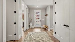 A hallway with white doors, a patterned rug, a bench, and framed artwork on the wall. - Grand Kanab'n: Rooftop Hot Tub, Red Rock Views (Kanab)
