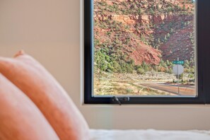 A window with a view of a mountainous landscape and a road sign for 'TOM'S CANYON RD.'