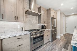 A modern kitchen with wooden cabinets, a stainless steel range, and a built-in oven.